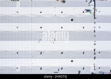 Dach des Industriegebäudes. Bauarbeiter Installation von Lüftungsanlagen auf einem großen Lagergebäude. Luftaufnahme von oben. Stockfoto