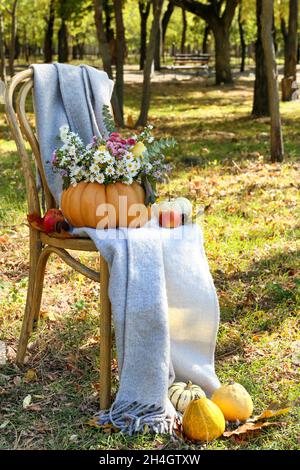 Strauß Herbstblumen in Kürbis auf Stuhl im Freien Stockfoto