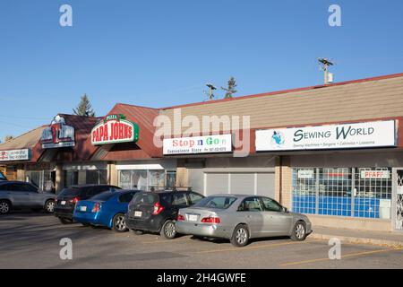 Geschäfte für kleine Unternehmen in einem Einkaufszentrum mit Näherei, Supermarkt, Pizzeria und Restaurant. Stockfoto