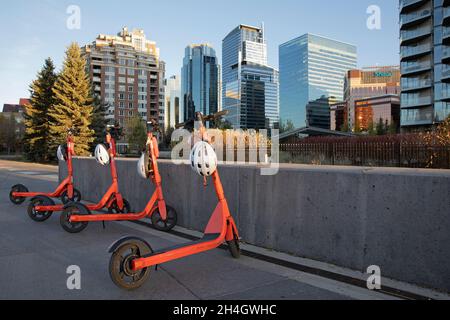 Reihe von gemeinsam genutzten E-Scootern zur Miete in der Innenstadt, mit dem weltweit ersten App-gesteuerten Helmschloss, das bei jeder Vermietung einen Schutzhelm bietet. Stockfoto