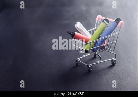 Einwegvapes in einem Warenkorb auf schwarzem Hintergrund. Moderne elektronische Zigaretten. Stockfoto