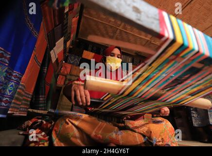 Lombok, West Nusa Tenggara, Indonesien-25. Oktober 2021: Eine Frau webt mit einem traditionellen Webstuhl Stockfoto