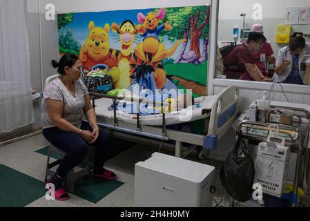 Eine Mutter schaut in einer Kindernotaufnahme in einem der städtischen Krankenhäuser in der Hauptstadt auf ihren kleinen Jungen, der an Atemwegserkrankungen leidet Stockfoto