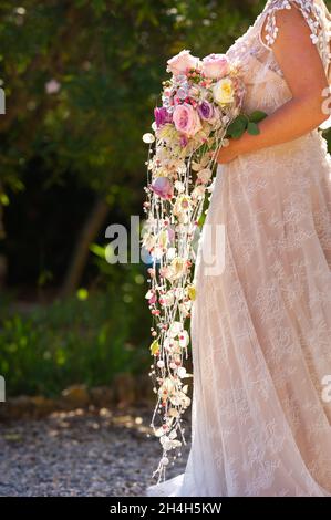 Ein ungewöhnlicher länglicher Brautstrauß in den Händen der Braut. Stockfoto