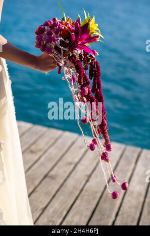 Ein ungewöhnlicher länglicher Brautstrauß in den Händen der Braut. Stockfoto