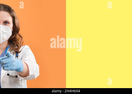 Ein Arzt in Uniform zeigt seinen Finger nach vorne auf Sie, Studiohintergrund Stockfoto