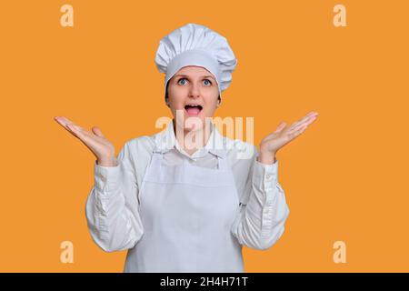 Enthusiastische Köchin mit einem fröhlichen Lächeln auf ihrem Gesicht auf einem Studiohintergrund, einem Mockup-Kopierraum Stockfoto