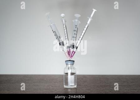 Eine Impfstoffflasche mit 4 Spritzen. Eine vierte Dosis Covid-19 Impfstoff Booster Shot Konzept. Stockfoto