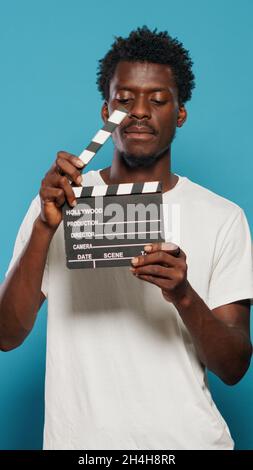 Porträt eines Mannes mit Klapperbrett, um Szenen in der Filmindustrie zu schneiden. Fröhliche Person, die Kreidetafel für Filmproduktionen und Filmaufnahmen im Studio verwendet. Junger Erwachsener mit Klatschbrett Stockfoto