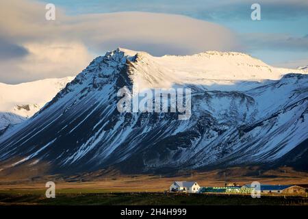 Bergpanorama mit Schnee und einem Bauernhof, bei Langaholt, Snaefellsnes, Westisland, Island Stockfoto