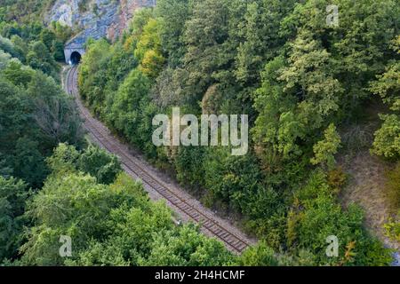 Drohnenansicht des Canyons, der vom Fluss Cris in Rumänien geschnitten wurde, in der Nähe von Vadu Crisului mit Felsformationen, bewaldeten Hügeln und den Bahngleisen Stockfoto