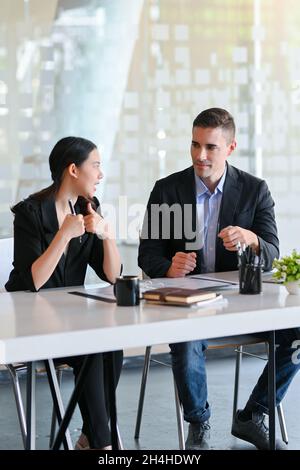 Geschäftsfrau und Geschäftsmann, die während der Kaffeepause im modernen Büro ein tolles Gespräch führen. Stockfoto