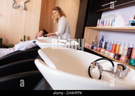 Blick auf Waschbecken und Friseursalon, der den Gästen die Haare wäscht Stockfoto