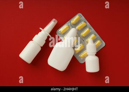 Leere Flaschen Nasenspray und Pillen auf rotem Hintergrund Stockfoto