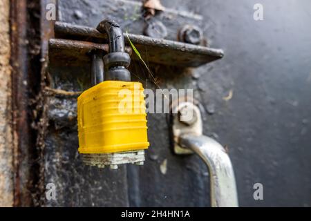 Geschlossenes gelbes Schloss an der schwarzen Stahltür mit Griff. Stockfoto