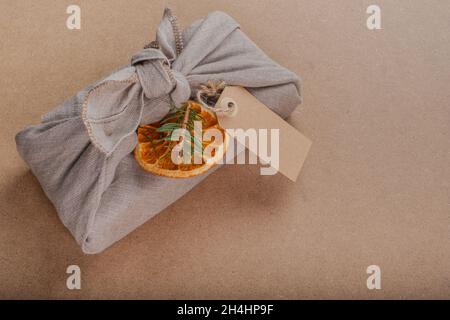 Furoshiki Geschenk in umweltfreundlichen wiederverwendbaren Stoff-Paket. Kleinunternehmen, ethische Shopping-Idee. Weihnachten ohne Verschwendung. Freier Speicherplatz für Text. Postkarte. Stockfoto