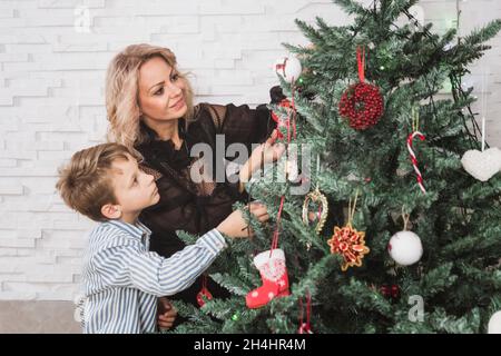 Mutter und ihr Sohn sind zu Hause zu Weihnachten geschmückt. Familienwunderzeit. Frohe Weihnachten und Frohes neues Jahr. Weißes Konzept Stockfoto