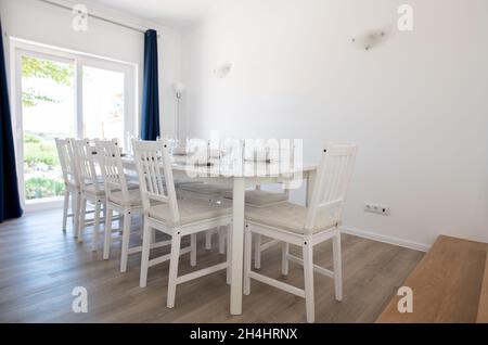Moderner Speisesaal mit weißen Wänden und weißem Tisch und Stühlen Stockfoto