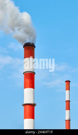 Rot und weiß lackierte Rauchschornsteine vor dem blauen Himmel. Stockfoto