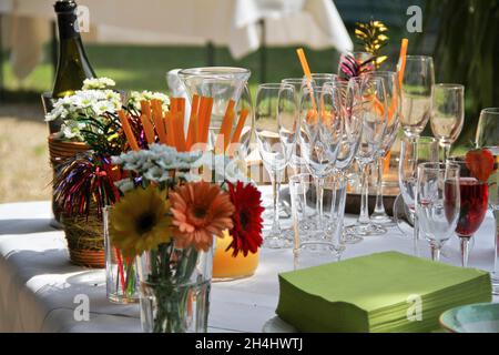 Tisch mit Gläsern, Servieren, Blumen und Champagner-Flasche für die Party vorbereitet Stockfoto