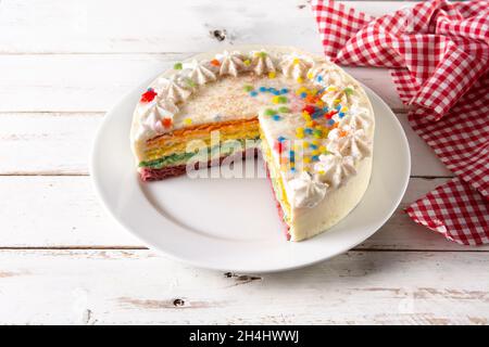 Regenbogenschicht-Kuchen auf weißem Holztisch Stockfoto