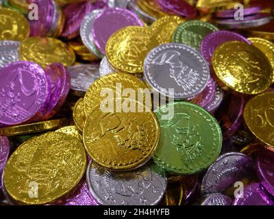 Nahaufnahme eines Stapels farbenfroher, runder Schokoladenpralinen mit Münzen, eingewickelt in glänzendes Ketteöl Stockfoto