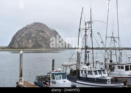 MORRO BAY, VEREINIGTE STAATEN - Jul 01, 2019: Die Fischerboote am Hafen in Morro Bay, Kalifornien an einem bewölkten Tag auf Morro Rock Hintergrund Stockfoto