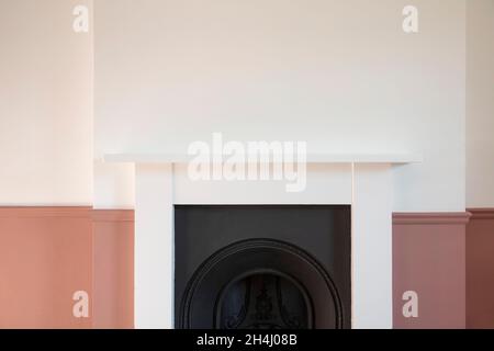 Viktorianischer Holzkamin, umgeben von weißen und rosafarbenen Wänden Stockfoto