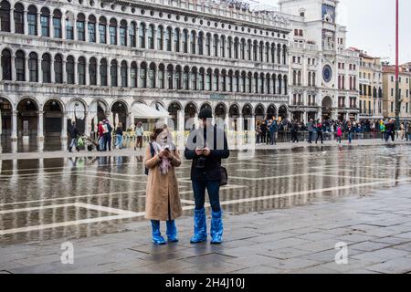 Venedig, Italien. November 2021. Touristen gehen bei einer Flut am 3. November 2021 in Venedig, Italien, auf einem überfluteten Markusplatz spazieren. In diesen Tagen ist Venedig aufgrund der hohen Flut für den Klimawandel unter Wasser, und Mose ist aktiviert, aber nicht ausreichend. © Simone Padovani / Erwachen / Alamy Live News Stockfoto