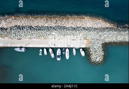 Luftdrohnenansicht von Fischerbooten, die am Hafen festgemacht sind. An Wellenbrechern festgemacht. Stockfoto