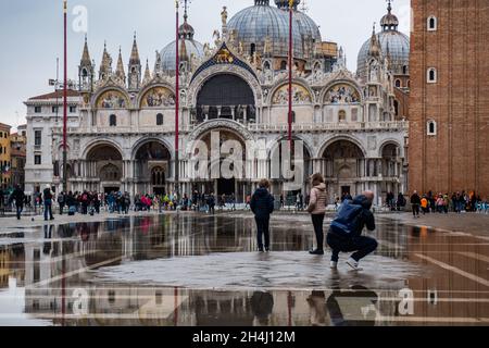 Venedig, Italien. November 2021. Touristen gehen bei einer Flut am 3. November 2021 in Venedig, Italien, auf einem überfluteten Markusplatz spazieren. In diesen Tagen ist Venedig aufgrund der hohen Flut für den Klimawandel unter Wasser, und Mose ist aktiviert, aber nicht ausreichend. © Simone Padovani / Erwachen / Alamy Live News Stockfoto