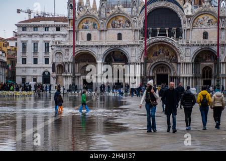 Venedig, Italien. November 2021. Touristen gehen bei einer Flut am 3. November 2021 in Venedig, Italien, auf einem überfluteten Markusplatz spazieren. In diesen Tagen ist Venedig aufgrund der hohen Flut für den Klimawandel unter Wasser, und Mose ist aktiviert, aber nicht ausreichend. © Simone Padovani / Erwachen / Alamy Live News Stockfoto