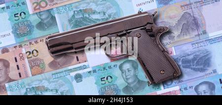 Chinesisches Verbrechen und Korruption, schmutziges Geldkonzept. Pistole auf China Yuan Renminbi Geldscheine Hintergrund. Stockfoto