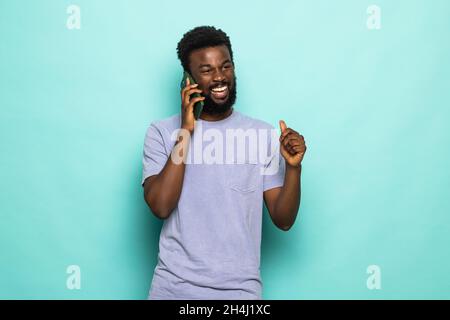 Porträt eines jungen afrikaners, der auf einem Mobiltelefon spricht und auf grünem Hintergrund steht, Stockfoto