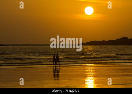 Die Menschen gehen am Meer bei Sonnenuntergang spazieren Stockfoto