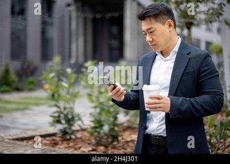 Geschäftsmann mit Kaffeetasse, die auf dem Smartphone anruft Stockfoto