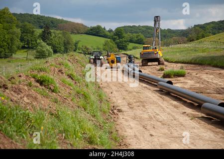 Unplugged Gas Pipeline in der Landseite diagonal von rechts diagonal durch Foto mit Gas Legemaschinen im Hintergrund Stockfoto