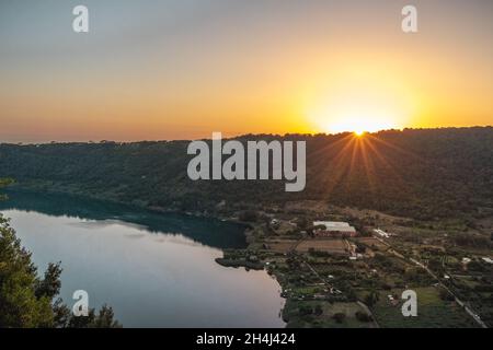 Sonnenuntergang über dem See in Nemi, Italien. Spiegelung des Mondes im Wasser. Stockfoto