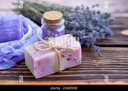 Lavendel-Spa-Produkte auf Holztisch. Körperpflegeprodukte mit Lavendel: Seife, Salz und getrocknete Lavendelblüten. Selektiver Fokus. Stockfoto