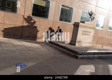 Mit einem Straßenaufkleber, der Fußgänger auffordert, 2 m voneinander entfernt zu bleiben, einer Covid-Erinnerung an soziale Distanzierung, geht eine Frau am 2. September 2021 in London, England, an der südlichen Grenze der London Bridge vorbei. Stockfoto