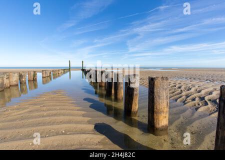 Strand mit reinem Sand, Fußabdrücke und Wellenbrecher mit einem blauen Himmel am Morgen Stockfoto