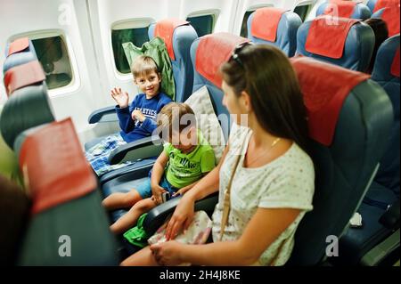 Zwei Jungen mit Mutter im kommerziellen Jet-Flugzeug, die im Urlaub fliegen. Stockfoto