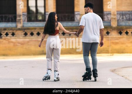 Paar im Rücken Skaten mit den Händen im Freien Stockfoto
