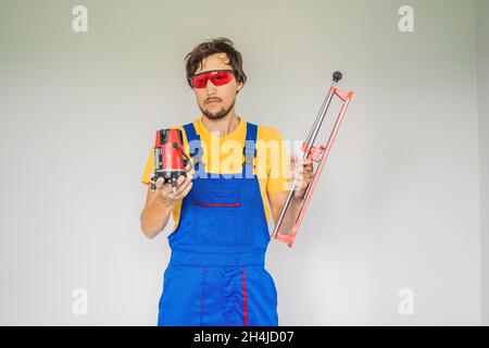 Ein Fliesenleger, ein Fliesenspezialist, hält einen Fliesenschneider in den Händen Stockfoto