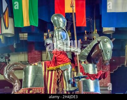 Ritter in Rüstung hält jousting Lanze auf gepanzerten Pferd unter bunten Fahnen. Stockfoto