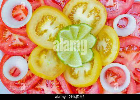 Tomatensalat mit Zwiebelringen garniert und ein Stück von Kalk. Stockfoto