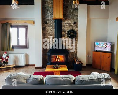 Warmer gemütlicher Kamin im Bergchalet mit echtem Brennholz. Gemütliches Winterkonzept. Winterurlaub Stockfoto