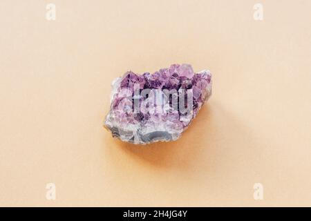 Purpurner Amethyst-Kristall auf hellbeigem Hintergrund, Nahaufnahme. Draufsicht. Stockfoto