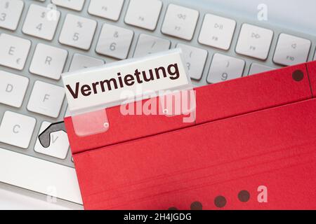 Das deutsche Wort für Miete ist auf dem Etikett einer roten Hängemappe zu sehen. Der Hängeordner befindet sich auf einer Computertastatur. Stockfoto