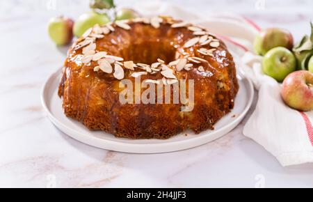 Hausgemachten Apfelkuchen schneiden und mit in Scheiben geschnittenen Mandeln garnieren. Stockfoto